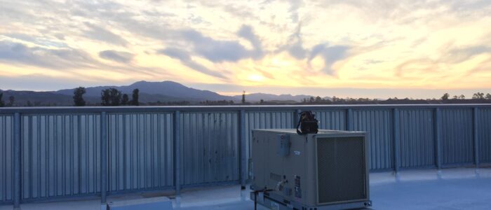 Legit Air, Ac unit on the roof with the view of a beautiful sunrise in the background.