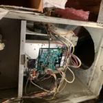 Certified Legit Air technician diagnosing and repairing a circuit board inside a modern furnace in a La Habra, California home attic space.