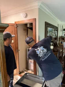 2 certified legit air technicians working on new furnace installed in the hallway of a Buena Park ca home