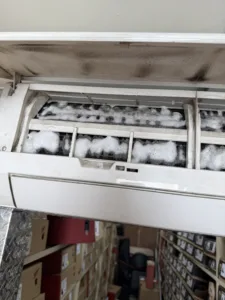 ac unit mounted on wall with coil being cleaned by foaming solution.